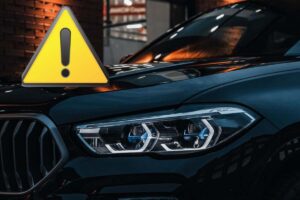 La parte anteriore di un'auto nera e il disegno del simbolo "attenzione"