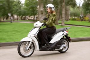 Una donna in sella ad uno scooter Piaggio