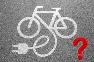 il disegno di una bici elettrica sull'asfalto e un un punto di domanda rosso