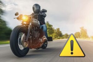 Una persona in moto e il segnale di pericolo
