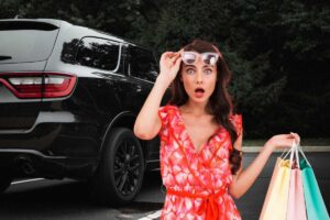 Un SUV nero e una donna stupita con delle borse in mano