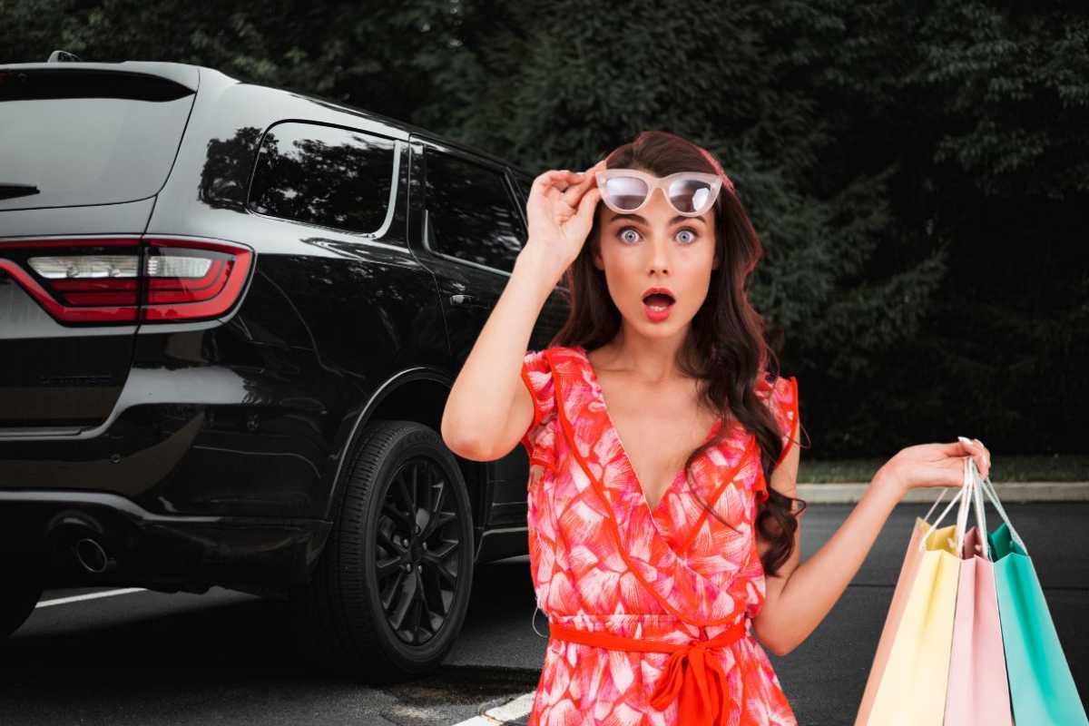 Un SUV nero e una donna stupita con delle borse in mano