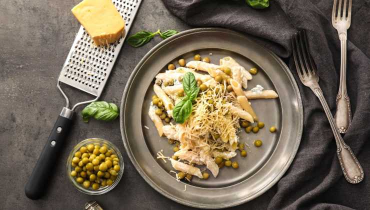 Un piatto di pasta con i piselli e formaggio grattugiato