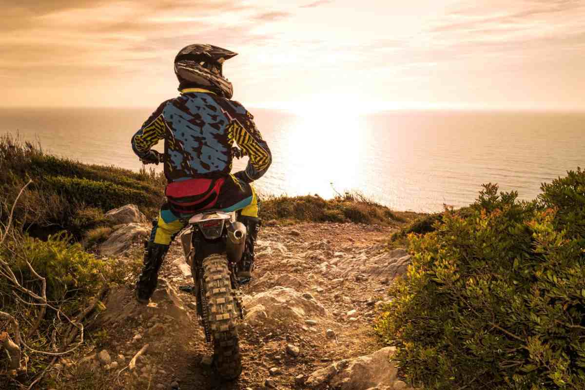 Un motociclista in sella ad una moto da enduro su sterrato
