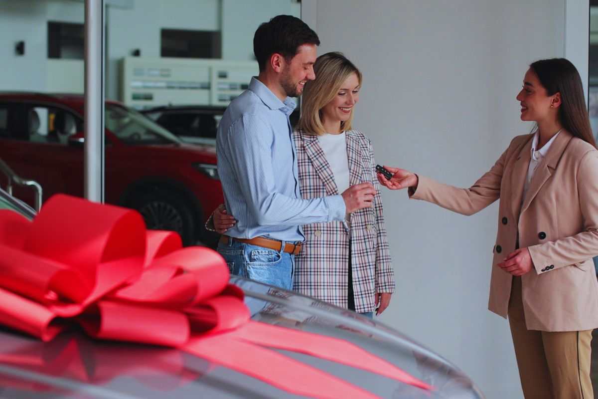 Venditrice che consegna chiavi auto ad acquirenti